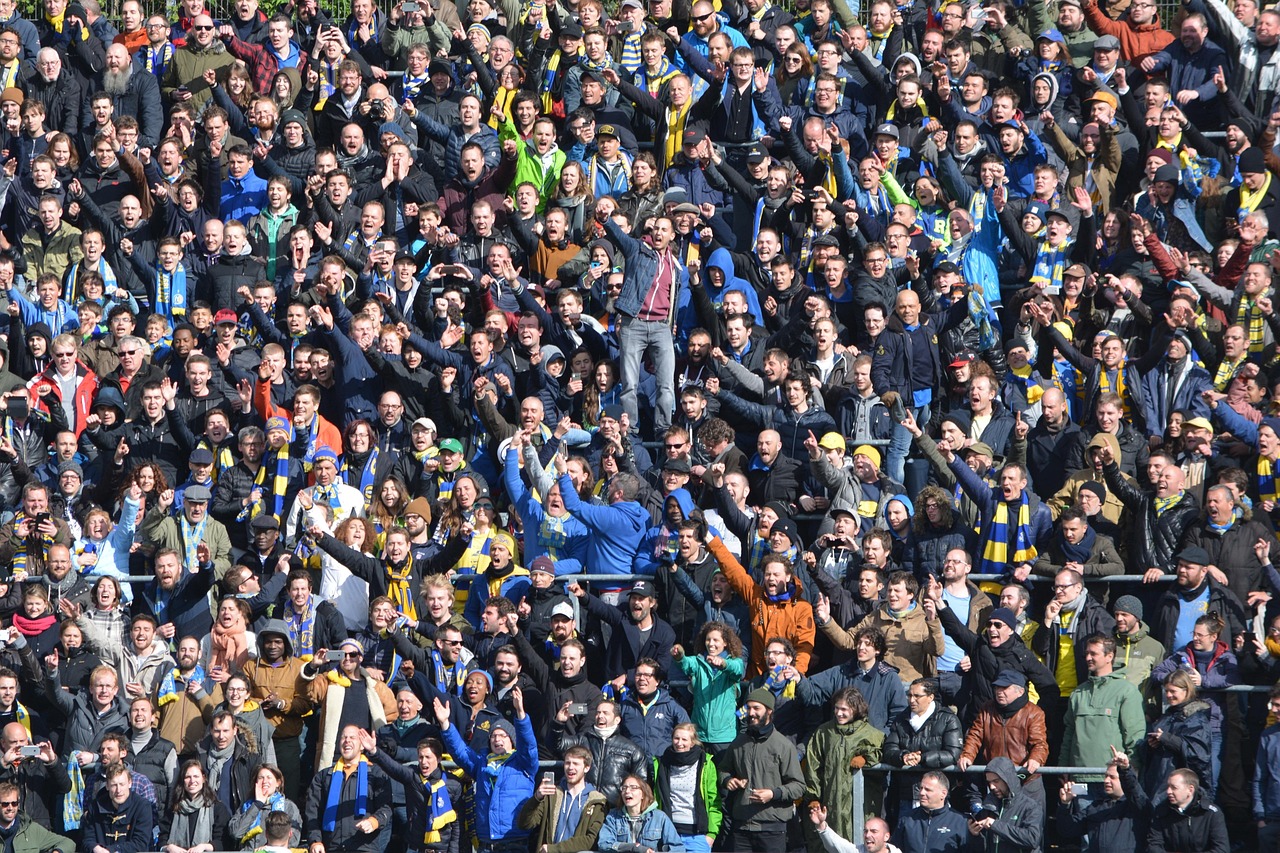Foule dense de supporters rassemblés dans les gradins d'un stade, vue de face.