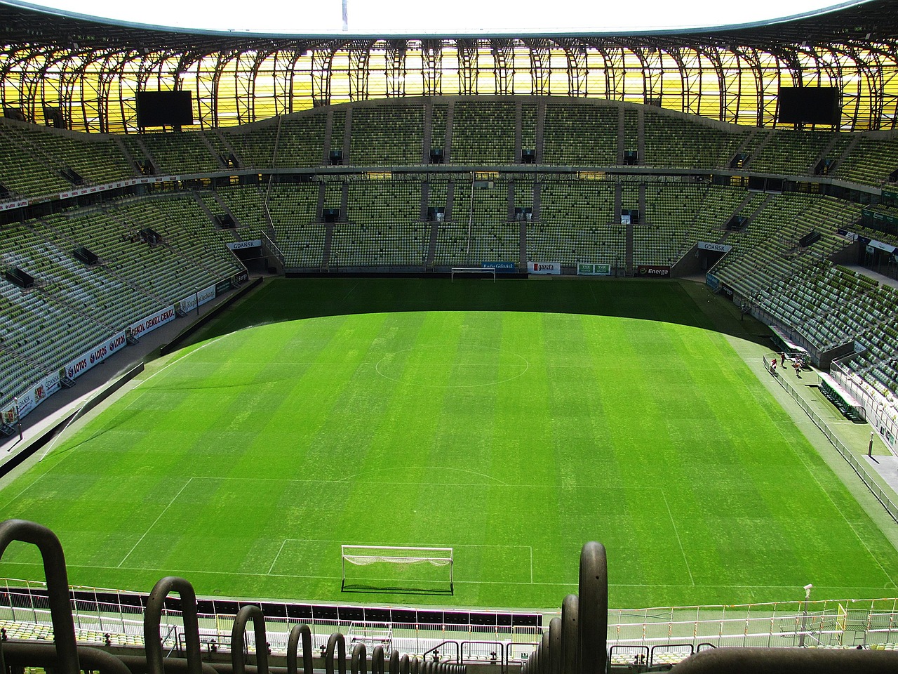 Stade de football vide aux sièges verts, vu depuis le haut d'une tribune sous un ciel clair
